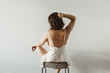 Young pretty woman in silk underwear sitting on black stool on white background. Fashion concept.
