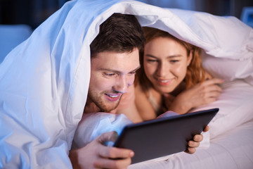 Sticker - technology, internet and people concept - happy couple using tablet pc computer in bed at night