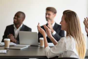 Sticker - Side view head shot smiling young woman applauding to speaker, mixed race millennial colleagues team feeling joyful, celebrating great work results, company success at business meeting at office.