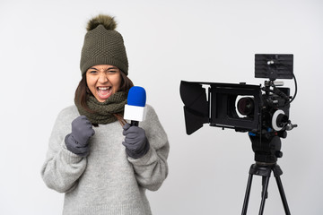 Reporter woman holding a microphone and reporting news over isolated white background celebrating a victory in winner position