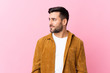 © luismolinero - Young handsome man with beard wearing a corduroy jacket over pink background looking to the side