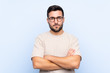 © luismolinero - Young handsome man with beard over isolated blue background keeping arms crossed