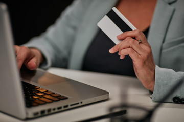 young caucasian businesswoman sitting in her office and using credit card to pay subscription for li