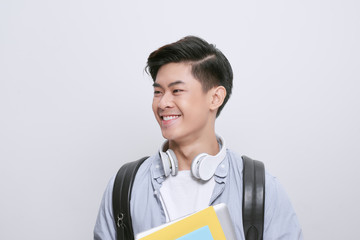 Wall Mural - Portrait of young asian student holding books isolated over white background