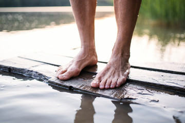 Sticker - Bare feet of woman standing by lake outdoors before swimming.