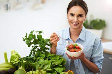 Healthy adult woman with green food in the kitchen