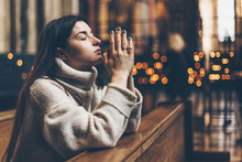 Religion, Faith, Harmony And People Concept: The Parishioner Of The Church Sits On A Bench With Her Hands Folded For Prayer And Heartily Prays. Copy Space