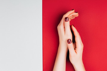 Red beautiful manicure on red and grey stylish background with copyspace. Flat lay style.