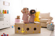 © New Africa - Cute little children playing with cardboard ship and binoculars at home