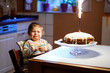 © Irina Schmidt - Cute crying little baby girl celebrating first birthday. Child scared and afraid of firework on baked cake, indoor. Toddler chil not happy