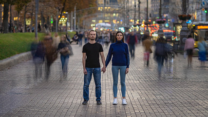 The man and woman stand on the crowded street and hold hands