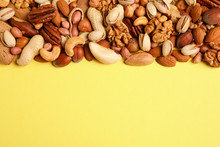 Different Delicious Nuts On Yellow Background, Flat Lay. Space For Text