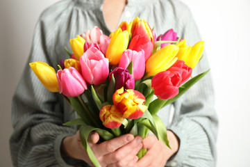 Woman holding beautiful spring tulips on white background, closeup