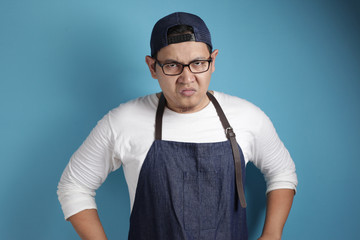 Wall Mural - Photo image of funny Asian male chef or waiter shows cynical unhappy angry facial expression