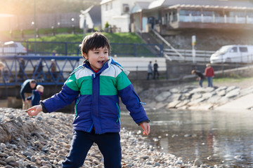 Active kid showing stone in his hand from the beach sand with bright light on spring or summer, little boy playing with the rock,Children exploring by the seaside, Play and lean from nature