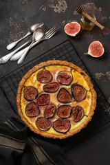 Wall Mural - Homemade quiche tart with figs, cream cheese and honey on dark brown background. Vintage style. Top view.