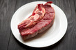 © Konstiantyn Zapylaie - Raw veal steak on a white plate on a black wooden background.