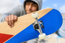 Close up of young man holding longboard or skateboard in the park .
