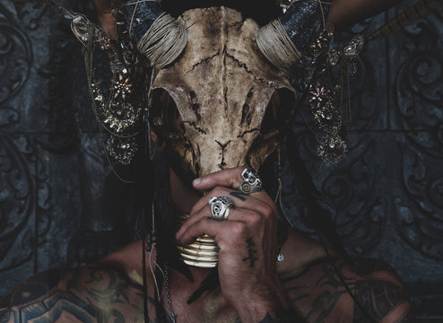 Fototapete - Tattooed masked skull ethnic pagan shaman sit on stage an ancient temple.