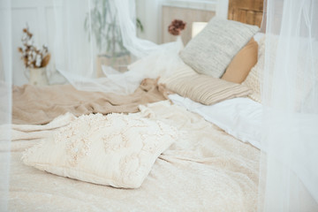 Beautifully decorated farmhouse look. cozy textiles blankets on the bed and pillows as an element of the interior in bright colors. Wooden bench. Selective focus