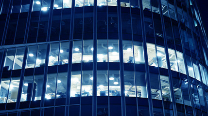 Night architecture - building with glass facade.Blue color of night lights. Modern building in  business district. Concept of economics, financial. Photo of commercial office building exterior. Abstra