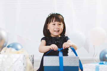 Wall Mural - toddler girl unpacking birthday gift box on her birthday party