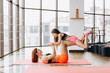 Beautiful young strong woman and charming little girl are smiling while doing yoga together in fitness hall
