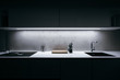 Modern kitchen in minimalist design during night with LED light strip and premium materials such as glass and concrete.Kitchen is complemented by basic kitchen utensils made of high quality materials.