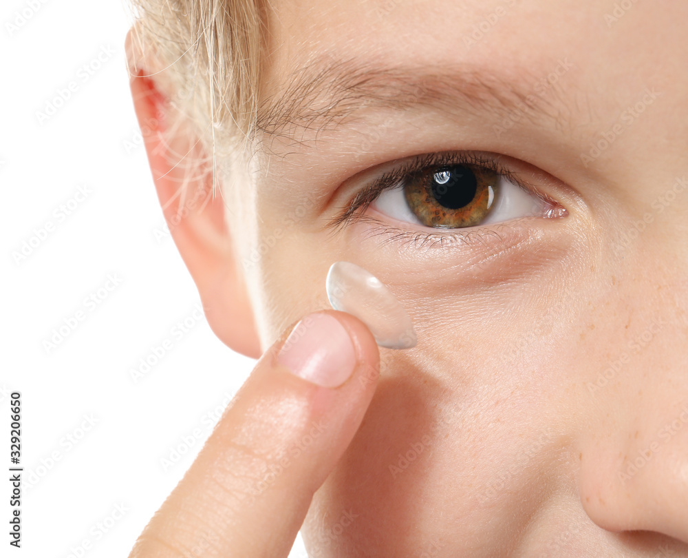 Little boy putting in contact lens on white background, closeup