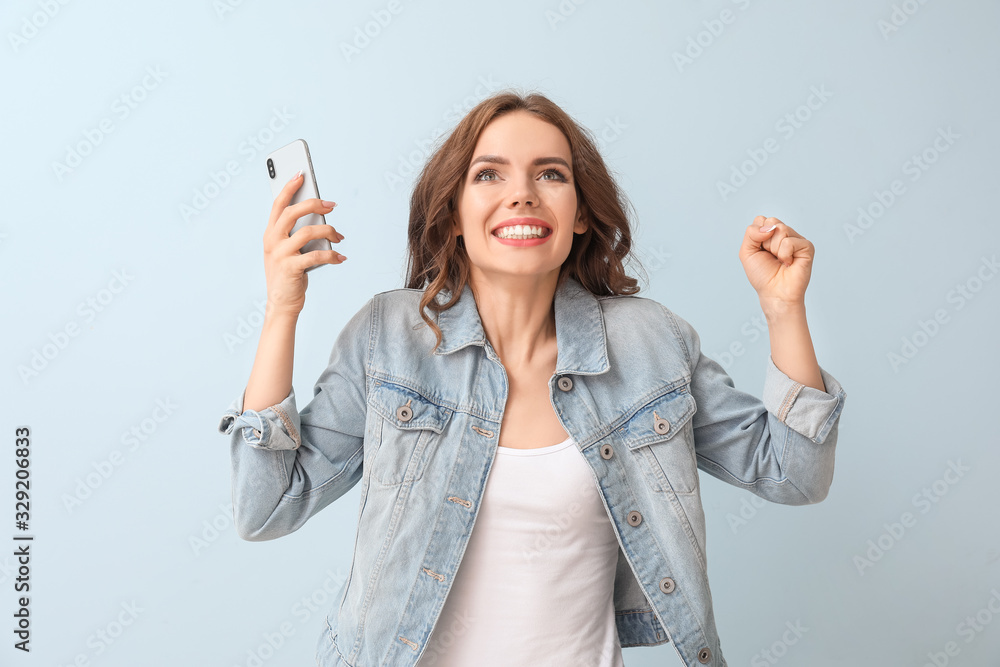 Happy young woman with mobile phone on color background