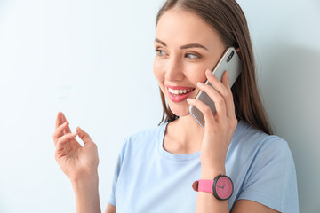 Sticker - Young woman talking by mobile phone on color background