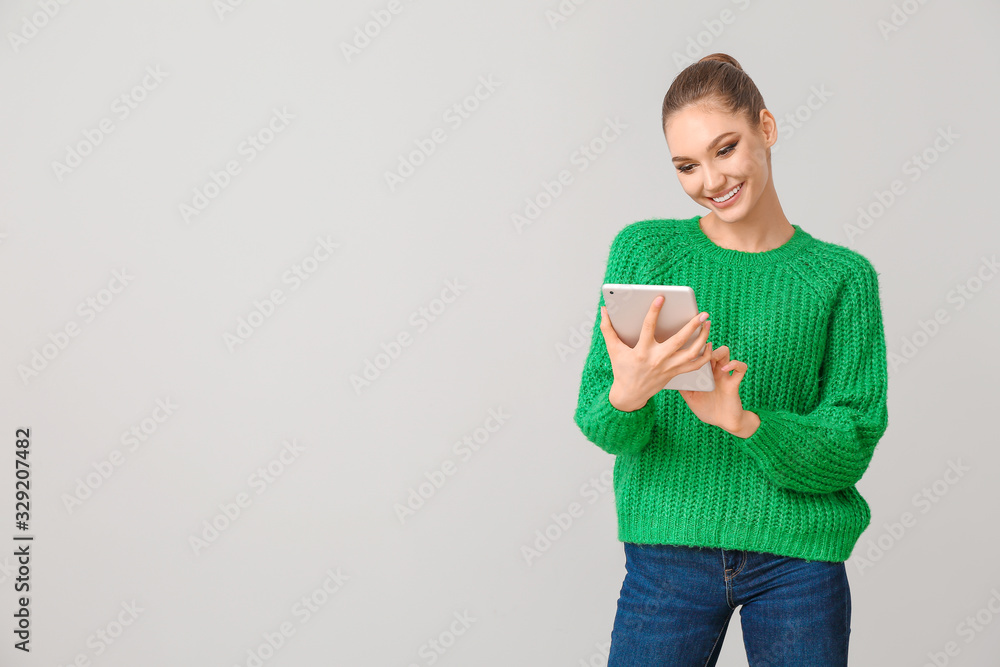Young woman with tablet computer on grey background