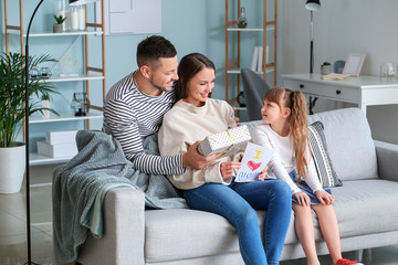 Wall Mural - Husband and little daughter greeting woman to Mother's Day at home