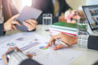 © Have a nice day  - close up of a businesswoman and businessman working together in a group in an office, using tablet device, books, notebook and a pen with work of statistics, charts and graphs on the paper documents