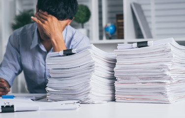 Wall Mural - Young asian exhausted businesssman with messy desk and stack of papers, working busy, overwork.