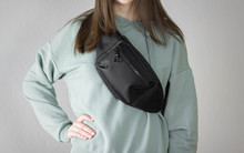 Girl In A Hoodie With A Bag On Her Chest. Close Up. Isolated On A Gray Background