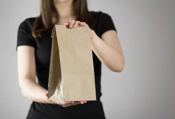 Girl holds a paper bag. Close up. Isolated on a gray background