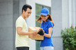 © DragonImages - Courier and customer checking delivery details in mobile application