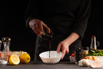 Wall Mural - Chef prepares salad dressing by pouring soy sauce to camellia shrimp. Freezing in motion, preparing healthy and wholesome food. On a black background for design.