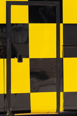 The bus body is covered in a checkerboard pattern. Yellow and black cell. Public transport design.