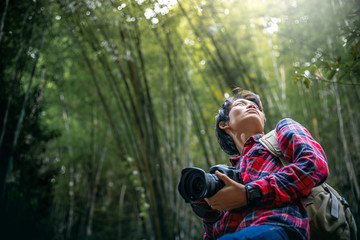 Tourists man standing and holding camera in forest