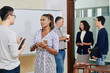 © DragonImages - Pretty young female entrepreneur with thermos in hands talking colleague after meeting