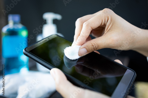 Hands of girl using cotton wool with alcohol to wipe on mobile phone to avoid contamination of Coronavirus,prevent contagious disease of Covid-19 virus,cleaning phone to eliminate of germs,bacteria