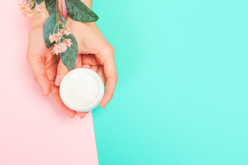 female  manicure. Beautiful young woman's hands with cream  on pastel background .