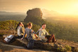 Group young tourists relaxes and watches during vacation colorful sunset on background of famous rocky plateau Lion peak, Sigiriya. Sri Lanka
