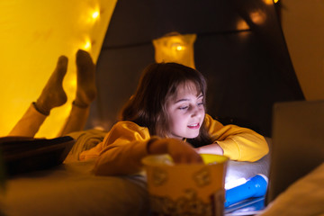 Wall Mural - little 11 year old girl using laptop under her home-made tent inside the living room.