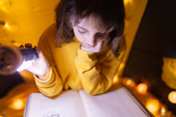 Wall Mural - young female child reading encyclopedia in a home made livingroom tent with light balls.
