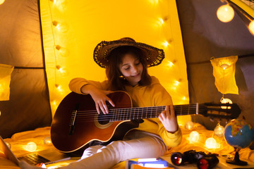 Wall Mural - little girl playing acoustic guitar under the tent in a living room.