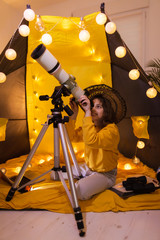 Wall Mural - small girl using telescope at home living room in a tent.