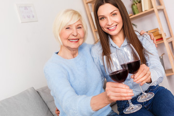 Adult woman and her senior mother with wine glasses in hands